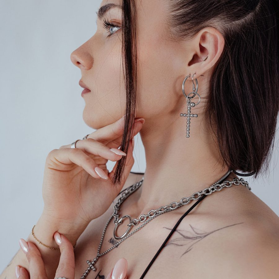 Frau mit silbernen Bubble Cross Hoops Ohrringen im Ohr, seitliches Profil