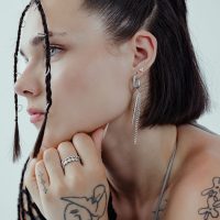 Frau mit schwarzen Haaren trägt silberne Triangle Ohrstecker