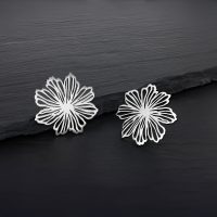Zwei silberne Blumen Ohrstecker aus Edelstahl auf dunklem Hintergrund