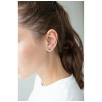 Silberne Herz Ohrstecker am Ohr einer Frau mit braunen Haaren, weißer Hintergrund