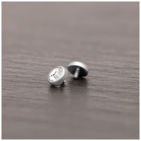Silberner Piercing-Aufsatz aus Titan mit klarem Kristall auf Holzoberfläche liegend