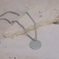 Silberne Kette mit rundem Anhänger auf hellem Steinboden