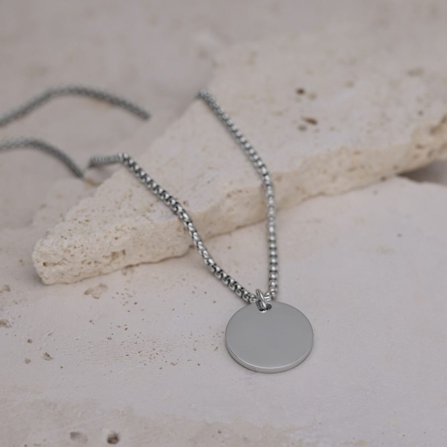 Silberne Kette mit rundem Anhänger auf hellem Steinboden