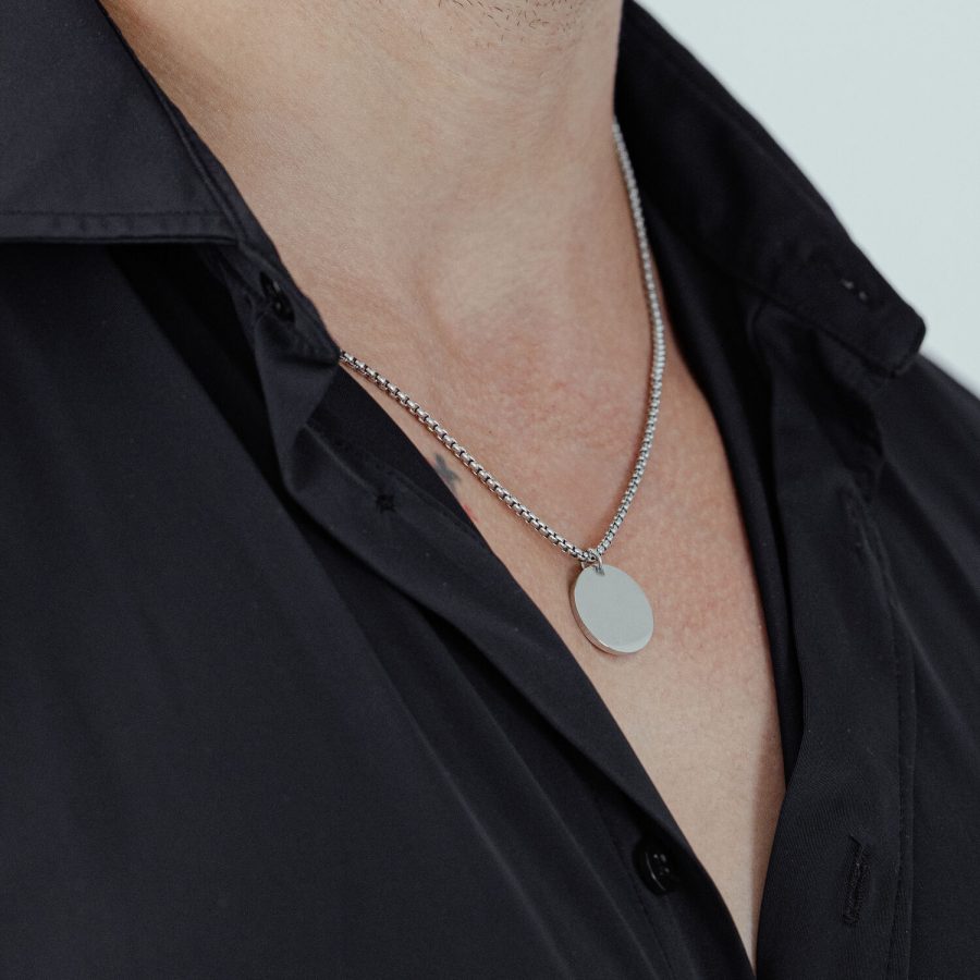Silberne Kette mit rundem Anhänger an einem schwarzen Hemd