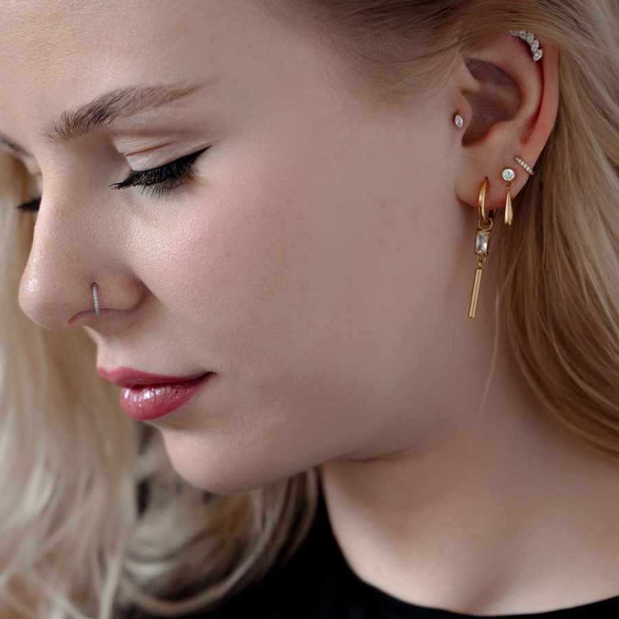 Frau mit mehreren Piercings, darunter ein goldener Kristall-Piercingaufsatz im Ohr.