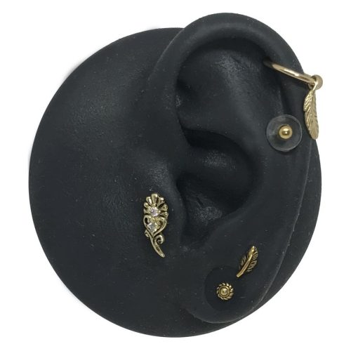 Schwarzes Silikon-Ohrenmodell mit goldenen Piercing-Aufsätzen auf weißem Hintergrund