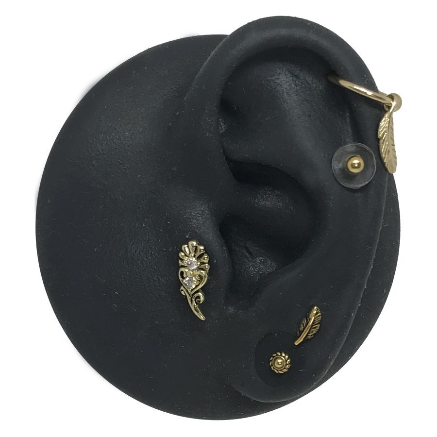 Schwarzes Silikon-Ohrenmodell mit goldenen Piercing-Aufsätzen auf weißem Hintergrund