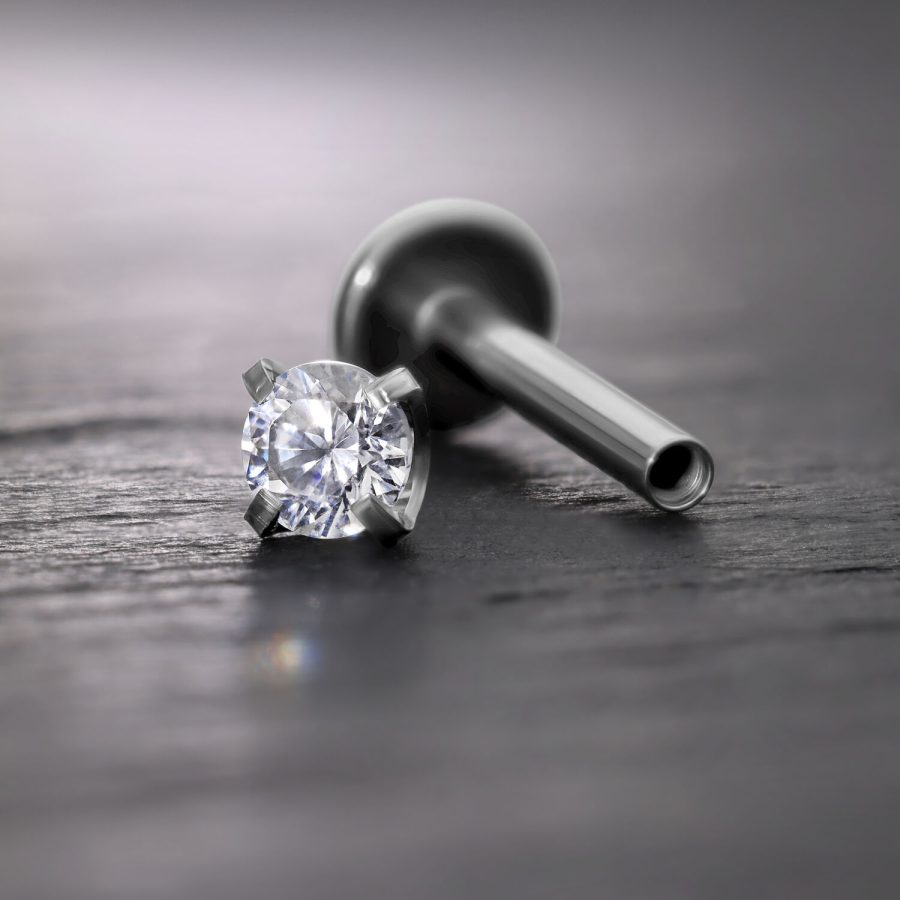 Silberner Prong Aufsatz mit Kristall für Innengewinde Labret auf grauem Hintergrund