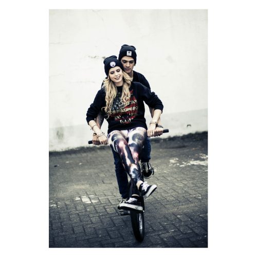 Junge Frau und Mann auf Fahrrad, tragen Wildcat® Sweatshirt in Schwarz mit USA-Design