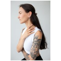 Frau mit langen Haaren und tätowierten Armen, trägt silberne Little Anchor Hoops Ohrringe