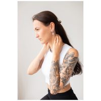Frau mit langen Haaren und Tattoos trägt Little Eye Hoops Ohrringe