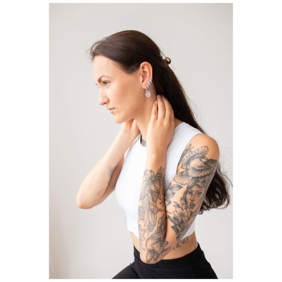 Frau mit langen Haaren und Tattoos trägt Little Eye Hoops Ohrringe