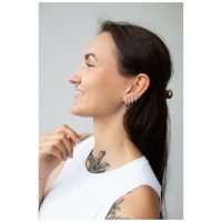 Frau mit langen, dunklen Haaren trägt silberne Little Sword Hoops Ohrringe auf hellem Hintergrund