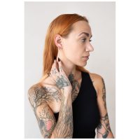 Frau mit roten Haaren trägt silberne Little Bar Hoops Ohrringe vor hellem Hintergrund