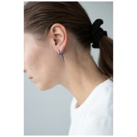 Frau mit silbernen Spike-Ohrringen, Haare im Zopf, weißer Hintergrund