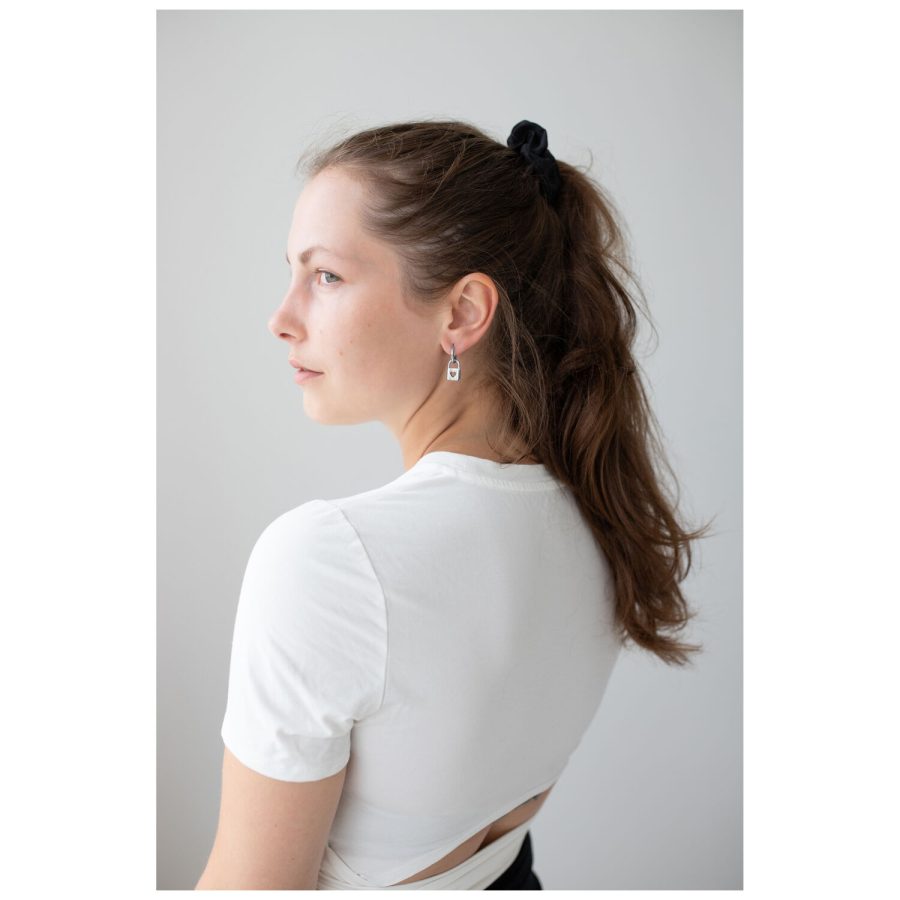 Frau mit langen Haaren trägt silberne Little Lock Hoops Ohrringe vor weißem Hintergrund