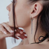 Silberne Edelstahl-Ohrringe mit Ketten an Ohr eines Models