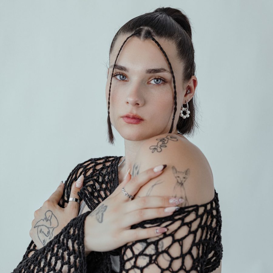 Frau mit Little Pearl Circle Hoops Ohrringen und schwarzem Oberteil vor neutralem Hintergrund