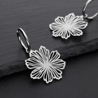 Zwei silberne Ohrringe mit Blumenmuster auf schwarzem Hintergrund