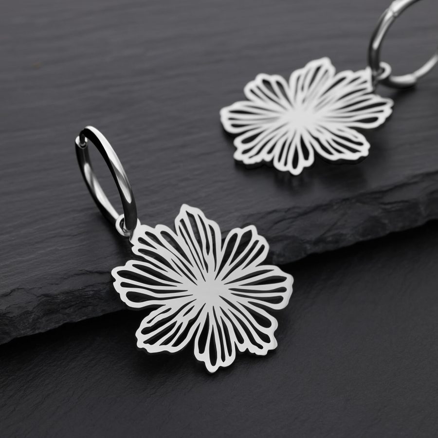 Zwei silberne Ohrringe mit Blumenmuster auf schwarzem Hintergrund