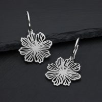 Silberne Edelstahl-Ohrringe mit Blumendesign auf dunklem Hintergrund