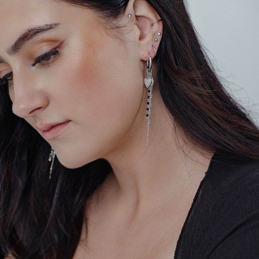 Frau mit langen, dunklen Haaren trägt silberne Bubble Heart Hoops mit Perle in ihrem Ohr