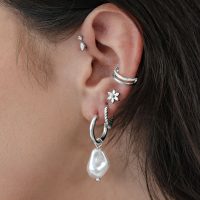 Silberne Barock-Perlenohrringe an einem Ohr mit mehreren Piercings.