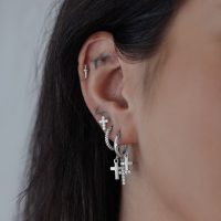 Silberne Creolen mit hängenden Kreuzanhängern an einem Ohr