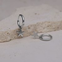 Zwei silberne Creolen mit Seestern-Anhänger auf hellem Stein