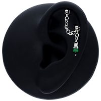Schwarze Piercingkette mit smaragdgrünem Kristall an schwarzem Ohrmodell