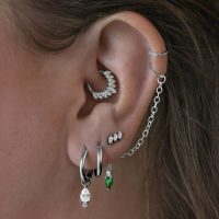 Smaragdgrüne Kristallpiercingkette am Ohr getragen, mit silberner Kette verbunden