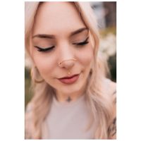Frau mit goldener Piercingkette an Nase und Ohr, im Freien