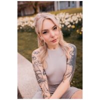 Frau mit Tattoos trägt eine silberne Piercingkette im Park