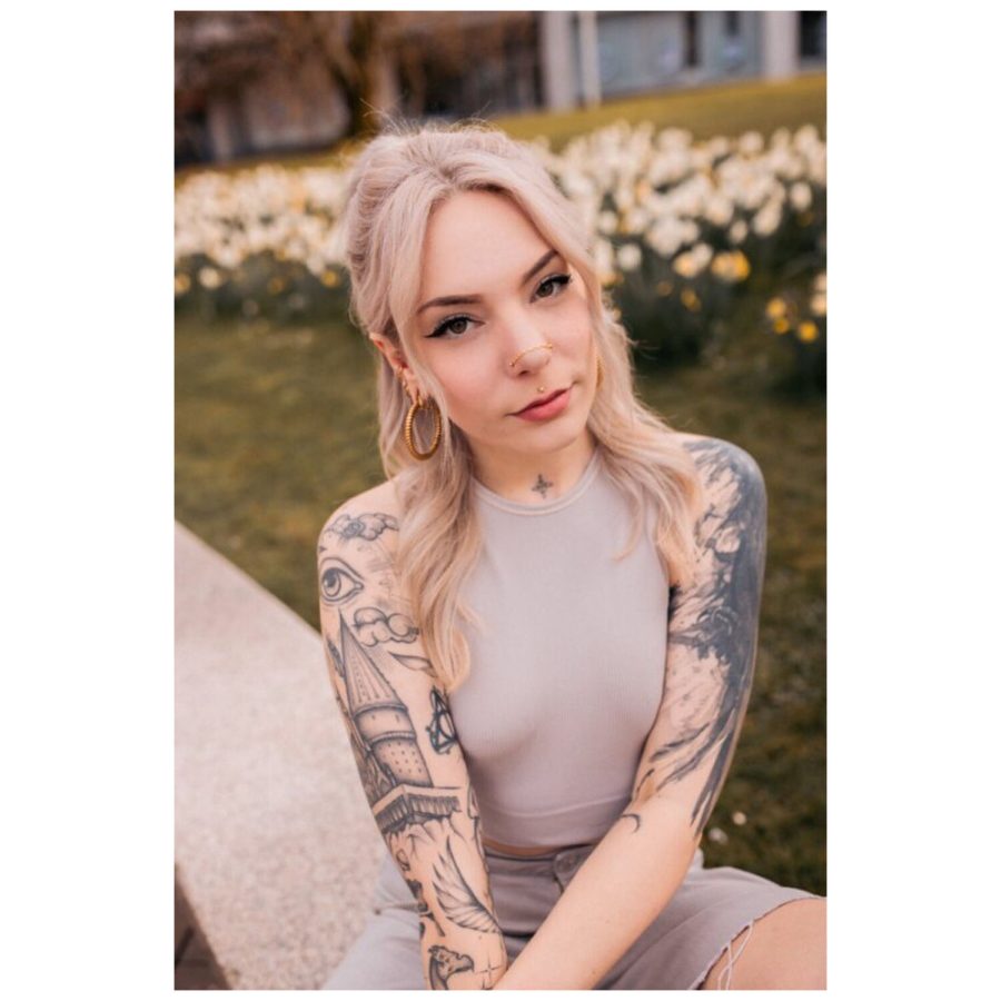Frau mit Tattoos trägt eine silberne Piercingkette im Park