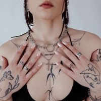 Frau mit Wildcat O Necklace aus Chirurgenstahl, Tattoos und Ringe
