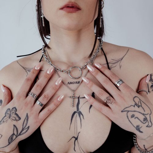 Frau mit Wildcat O Necklace aus Chirurgenstahl, Tattoos und Ringe