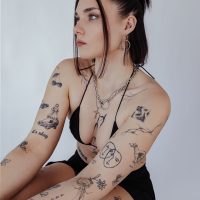Frau mit goldener O Halskette aus Chirurgenstahl, Tattoos sichtbar