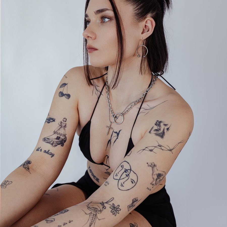 Frau mit goldener O Halskette aus Chirurgenstahl, Tattoos sichtbar