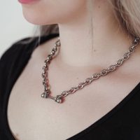 Silberne Barbell Halskette aus Chirurgenstahl auf einem schwarzen Oberteil getragen