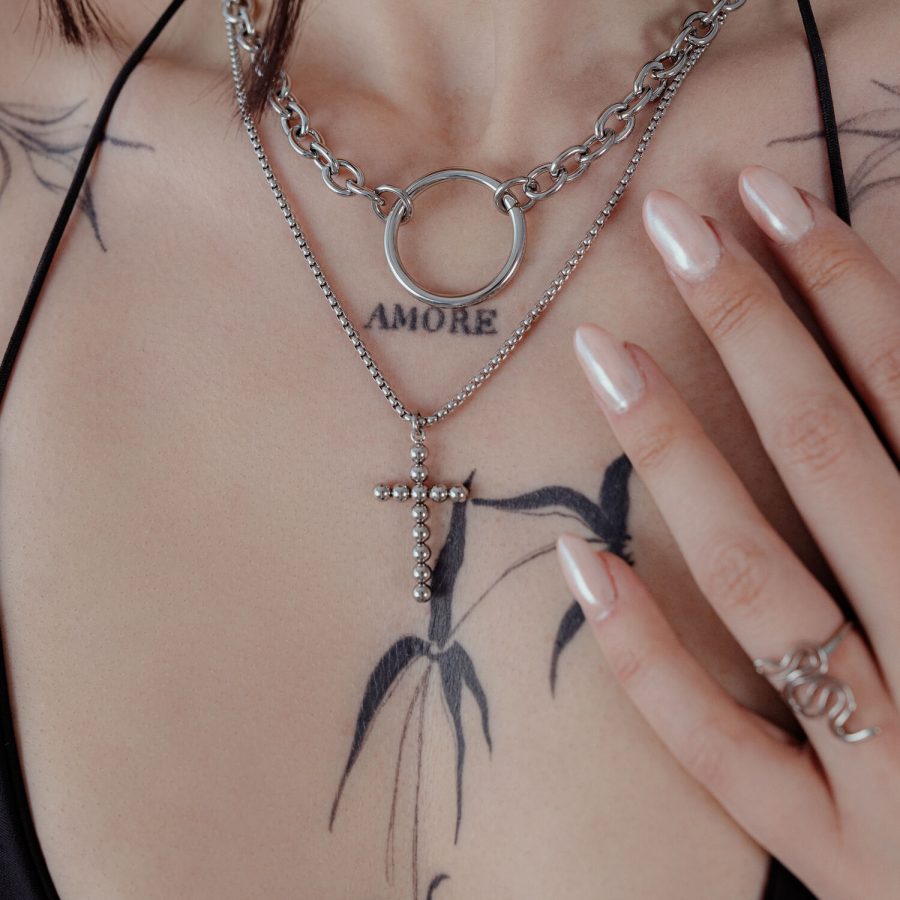 Silberne Bubble Cross Halskette an einer Frau mit Tattoos, Nahaufnahme