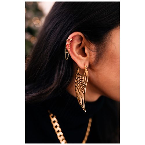 Nahaufnahme eines Ohres mit goldener Kette und Flügel-Ohrring, getragen von einer Person
