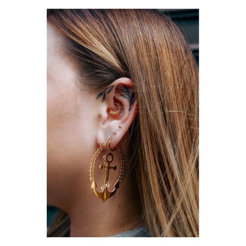 Frau mit goldenen Piercings im Ohr, darunter ein Little Balls Crystal Clicker
