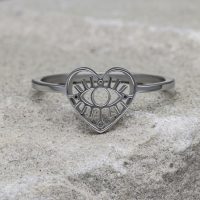 Silberner herzförmiger Ring mit Auge-Motiv auf grauem Stein