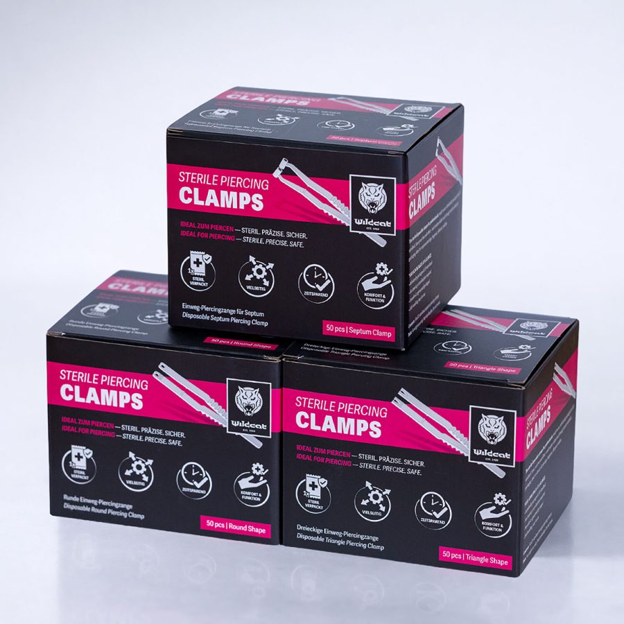 Drei schwarze Boxen mit Aufschrift 'Sterile Piercing Clamps' auf weißem Hintergrund