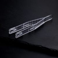 Klare sterile Triangel Piercingzange auf schwarzem Hintergrund, einzeln verpackt