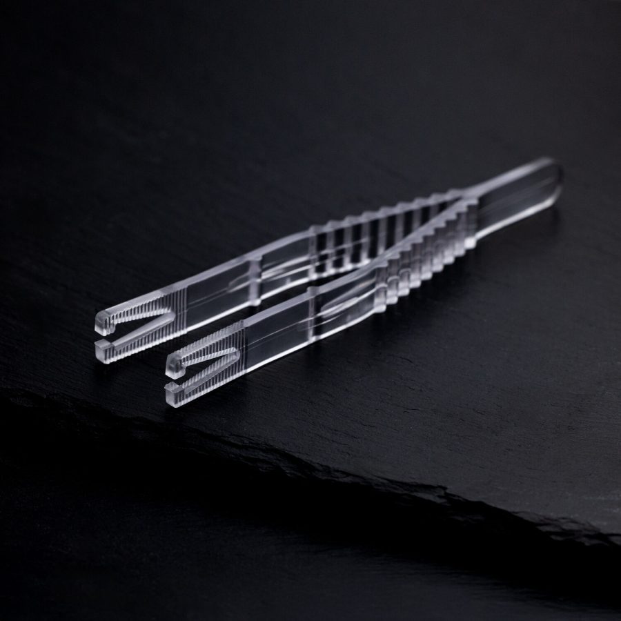 Klare sterile Triangel Piercingzange auf schwarzem Hintergrund, einzeln verpackt