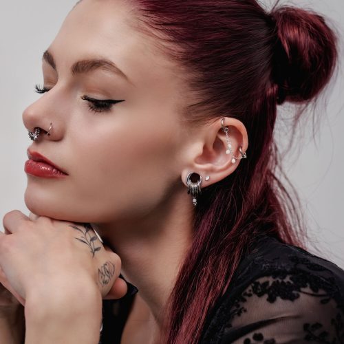 Frau mit eleganten Ohrpiercings und Kristall-Anhängern, rotes Haar