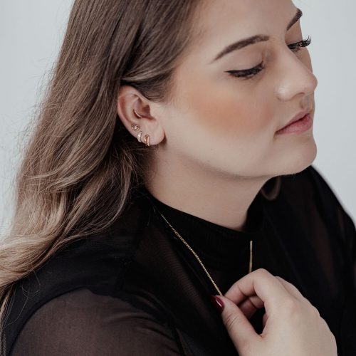 Frau mit Ohrpiercing, goldener Push Fit Crystal Lovely Eye Aufsatz, schwarzes Oberteil