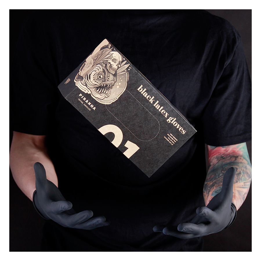 Person in schwarzem Shirt hält schwarze Piranha Latex-Handschuhe Schachtel vor dunklem Hintergrund