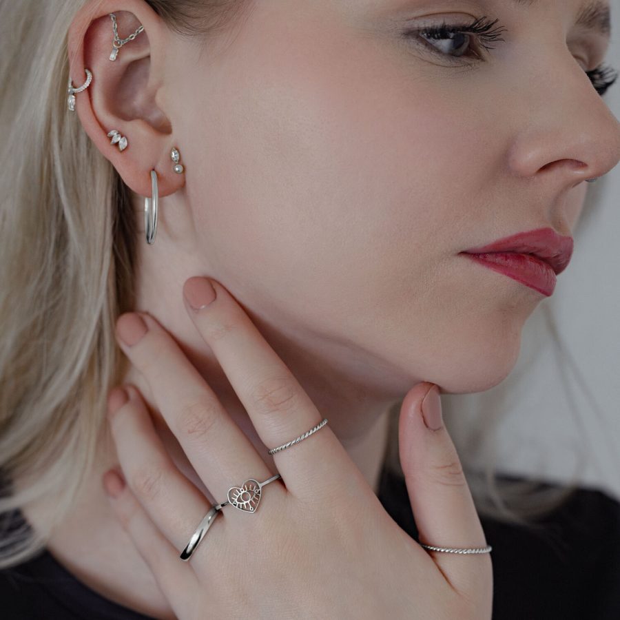 Frau mit mehreren Ohrringen, die einen silbernen Twisted Ring trägt
